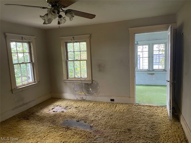 carpeted empty room featuring a wealth of natural light and ceiling fan