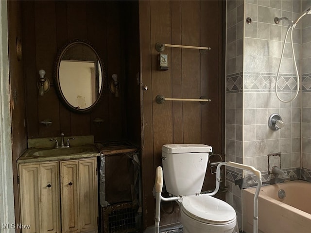 full bathroom featuring wood walls, washtub / shower combination, vanity, and toilet