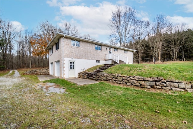 rear view of property with a garage and a yard