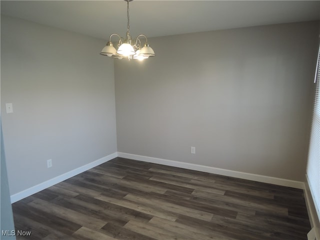 spare room with dark wood-type flooring and a chandelier