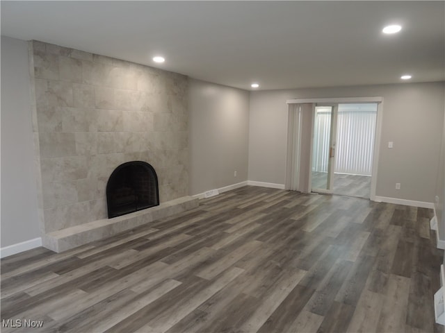 unfurnished living room with dark hardwood / wood-style flooring and a tile fireplace