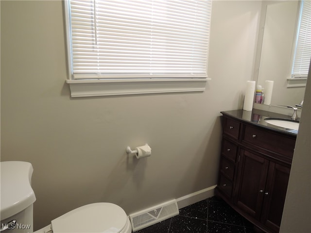 bathroom featuring a wealth of natural light, vanity, and toilet