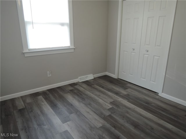 unfurnished bedroom featuring dark wood-type flooring and a closet