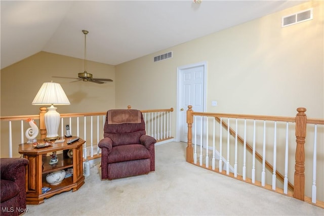 sitting room with an upstairs landing, visible vents, lofted ceiling, and carpet floors