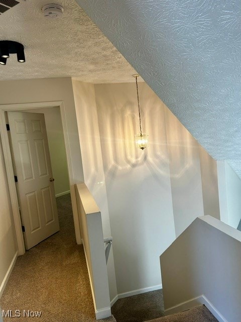 corridor with carpet floors and a textured ceiling