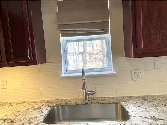 kitchen with light stone countertops, sink, and tasteful backsplash