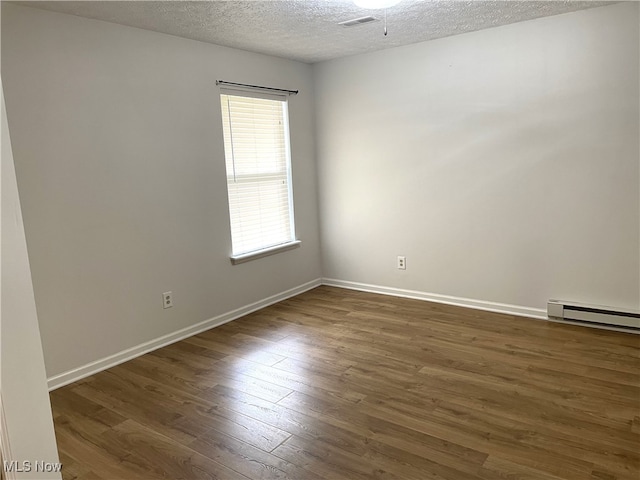 unfurnished room featuring a textured ceiling, a baseboard heating unit, and dark hardwood / wood-style flooring