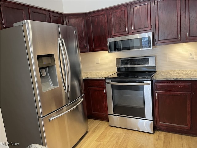 kitchen with decorative backsplash, light stone counters, light hardwood / wood-style floors, and stainless steel appliances