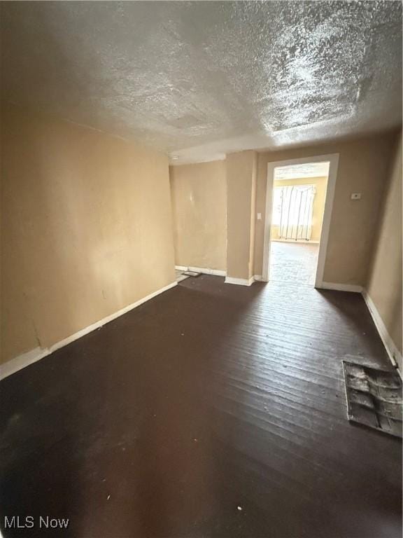 empty room with a textured ceiling and dark hardwood / wood-style flooring