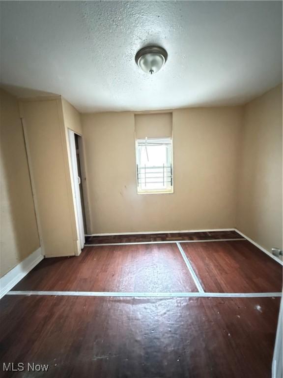 unfurnished bedroom featuring a textured ceiling and dark wood-type flooring