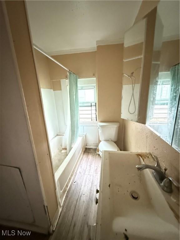 full bathroom with sink, hardwood / wood-style floors, shower / bath combo, and toilet