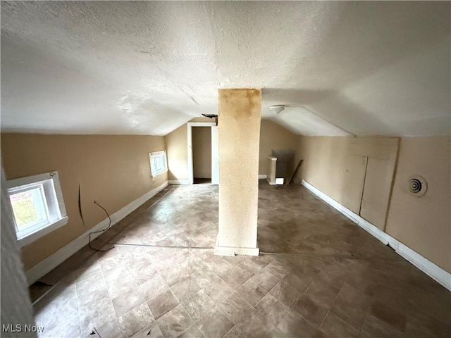 additional living space with a textured ceiling and lofted ceiling