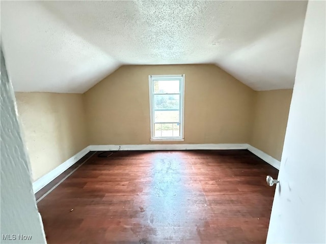 bonus room featuring a textured ceiling, lofted ceiling, and dark hardwood / wood-style floors