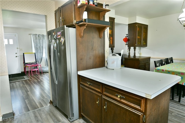 kitchen with kitchen peninsula, hanging light fixtures, dark brown cabinets, stainless steel fridge with ice dispenser, and dark hardwood / wood-style flooring