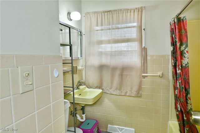 bathroom featuring shower / tub combo with curtain, sink, and tile walls