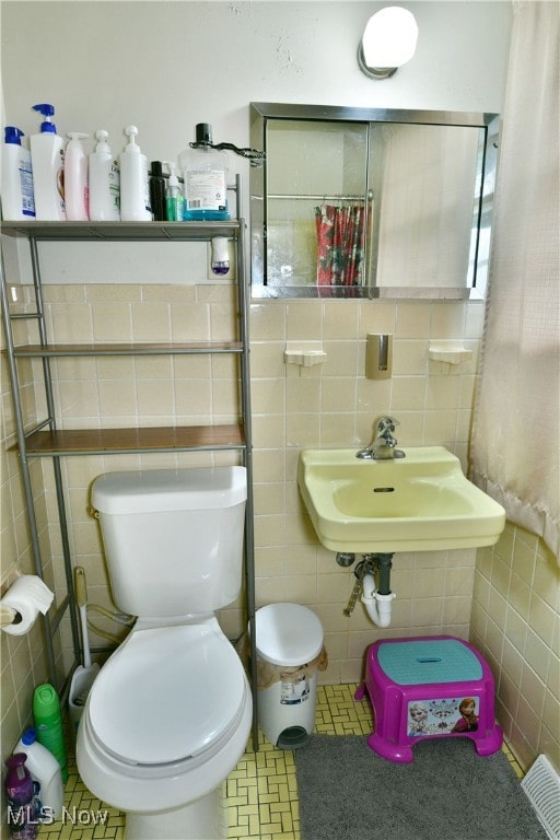 bathroom with tile walls, tile patterned floors, sink, and toilet