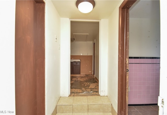 hallway with tile walls and light tile patterned flooring