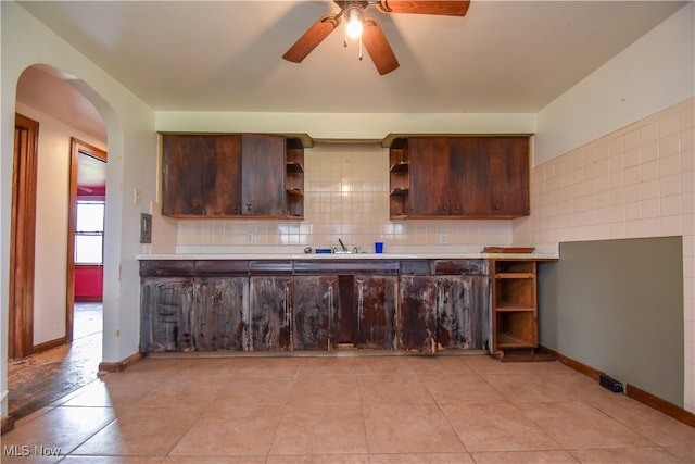 kitchen with light tile patterned floors, decorative backsplash, dark brown cabinetry, and ceiling fan