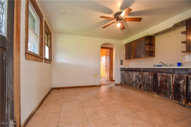 kitchen featuring backsplash, sink, light tile patterned floors, and ceiling fan