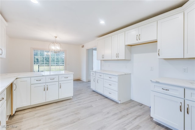 kitchen with light hardwood / wood-style floors, a chandelier, white cabinetry, and pendant lighting