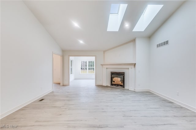 unfurnished living room with a skylight, light hardwood / wood-style flooring, and high vaulted ceiling