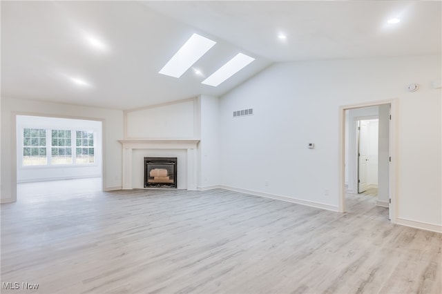 unfurnished living room with high vaulted ceiling, light wood-type flooring, and a skylight