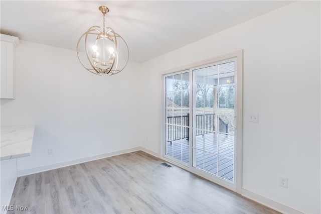 unfurnished dining area with a notable chandelier and light hardwood / wood-style flooring