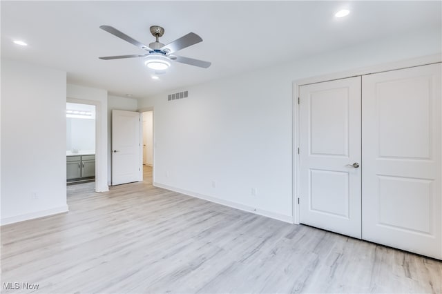 unfurnished bedroom featuring a closet, light hardwood / wood-style floors, ceiling fan, and ensuite bathroom