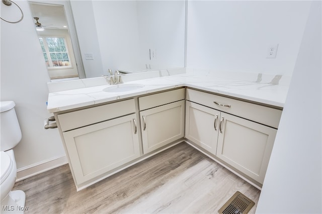 bathroom with toilet, vanity, hardwood / wood-style floors, and ceiling fan