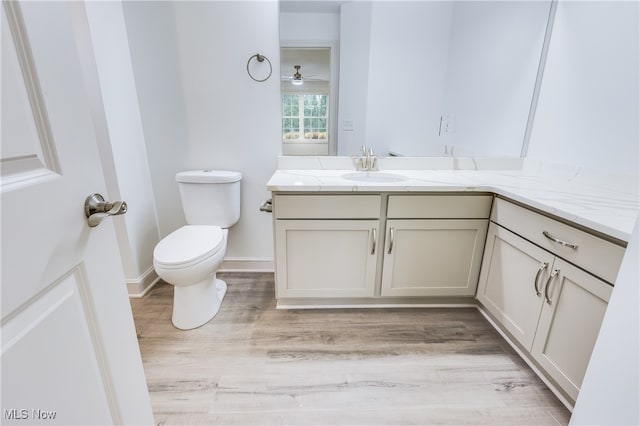 bathroom with vanity, hardwood / wood-style flooring, toilet, and ceiling fan