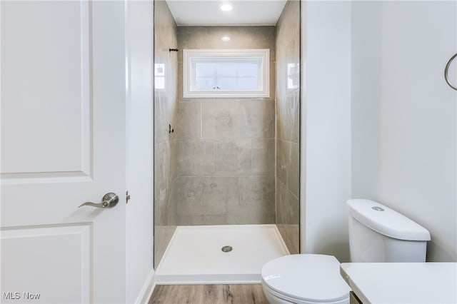 bathroom with toilet, vanity, wood-type flooring, and tiled shower