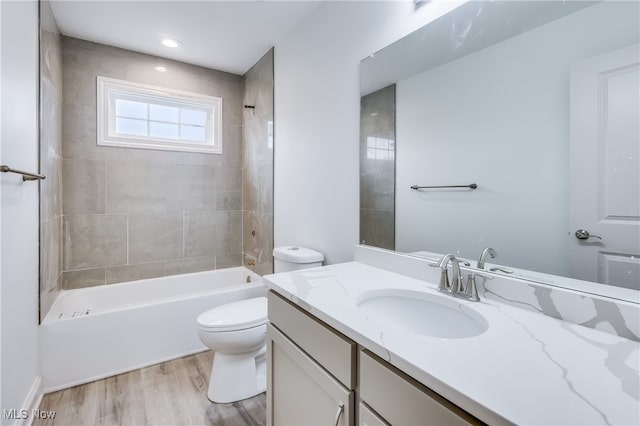 full bathroom featuring wood-type flooring, toilet, vanity, and tiled shower / bath