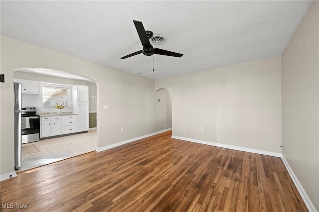 spare room with light hardwood / wood-style floors, ceiling fan, and a textured ceiling