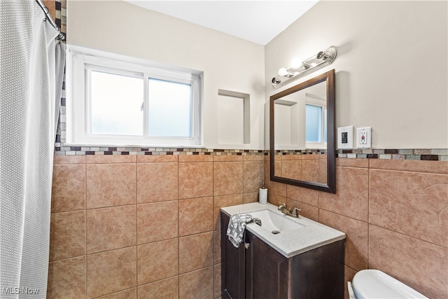 bathroom with toilet, vanity, and tile walls