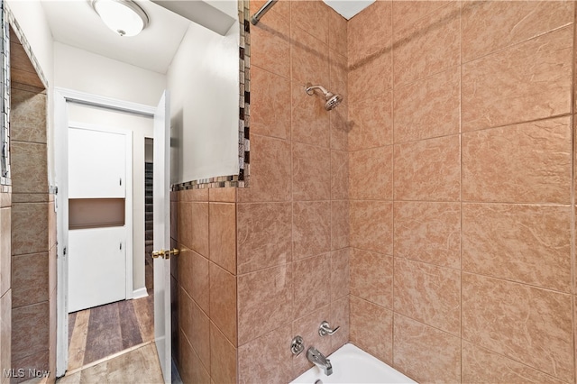 bathroom with tiled shower / bath combo, tile walls, and hardwood / wood-style floors