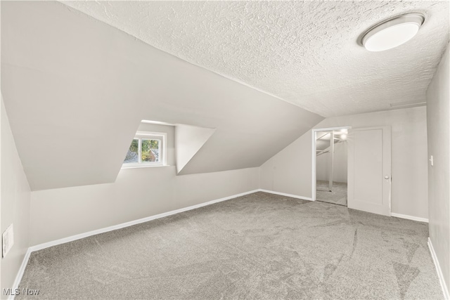 additional living space featuring a textured ceiling, carpet flooring, and lofted ceiling