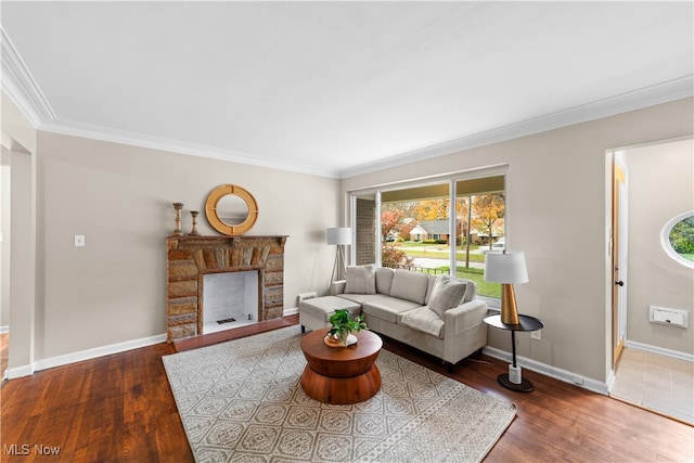 living room featuring dark wood-type flooring, a stone fireplace, and crown molding