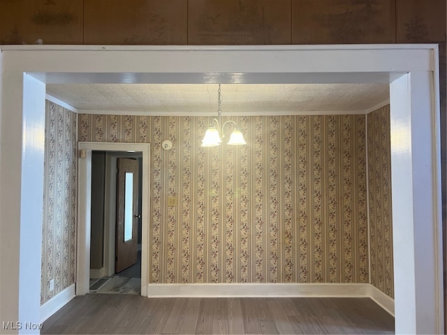 unfurnished dining area with a chandelier and hardwood / wood-style flooring