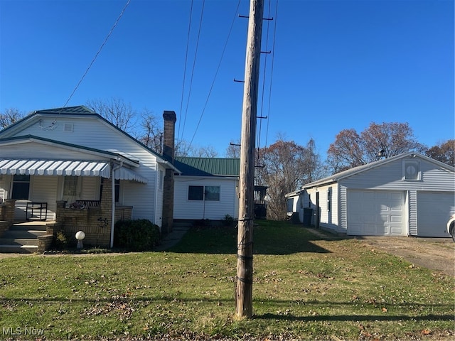 view of home's exterior featuring covered porch, a garage, an outbuilding, and a yard