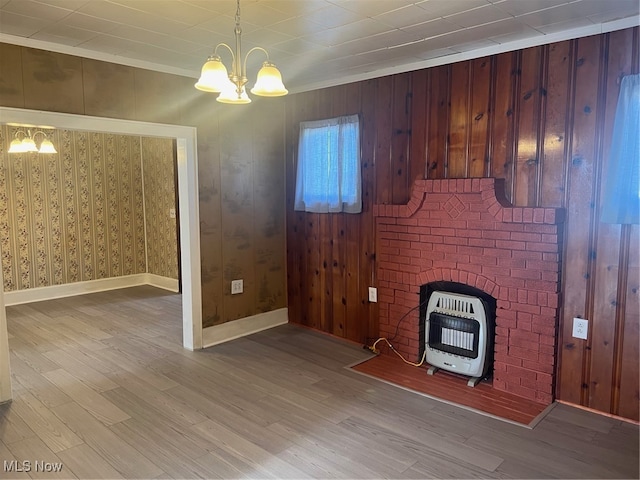 unfurnished living room featuring a chandelier, heating unit, light hardwood / wood-style floors, and crown molding