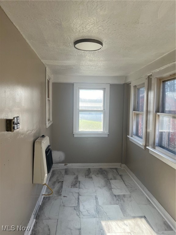 unfurnished room with heating unit and a textured ceiling