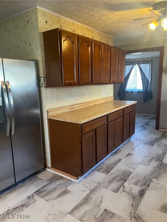 kitchen featuring ceiling fan, stainless steel fridge, and a textured ceiling