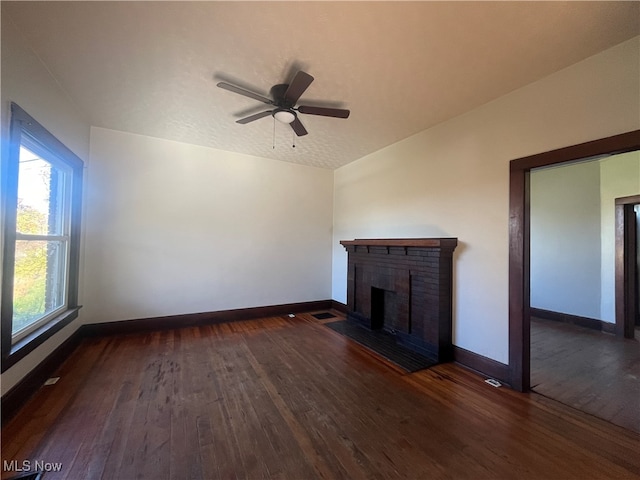 unfurnished living room with lofted ceiling, a textured ceiling, dark hardwood / wood-style floors, ceiling fan, and a fireplace