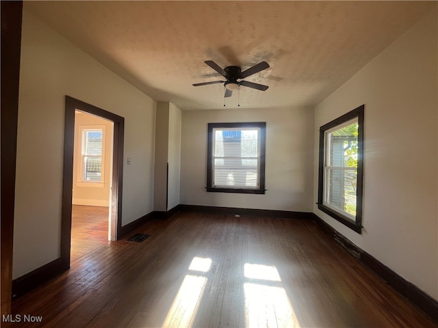 unfurnished room with ceiling fan, a healthy amount of sunlight, a textured ceiling, and dark hardwood / wood-style flooring