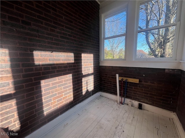 interior space with light hardwood / wood-style floors and brick wall