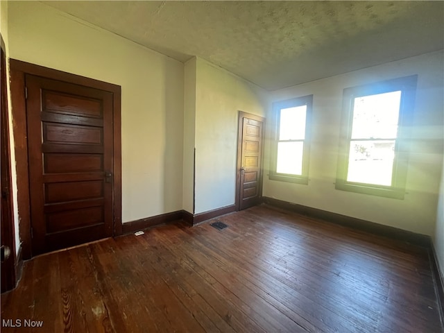 empty room featuring dark hardwood / wood-style floors and a textured ceiling