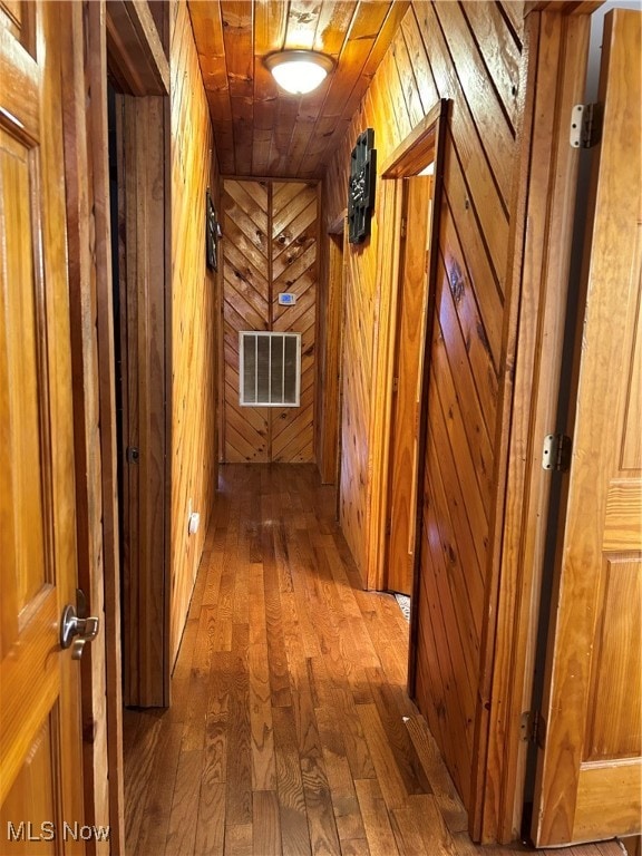 hallway with wood walls and wood-type flooring