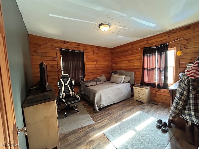 bedroom with wood walls and wood-type flooring