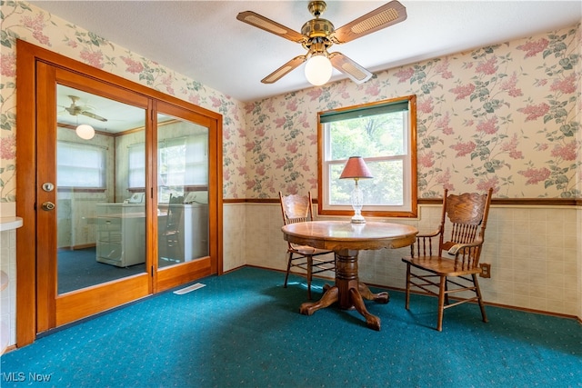 living area with ceiling fan and tile walls