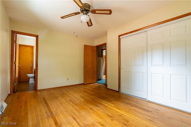 unfurnished bedroom featuring light wood-type flooring, ensuite bath, ceiling fan, and a closet